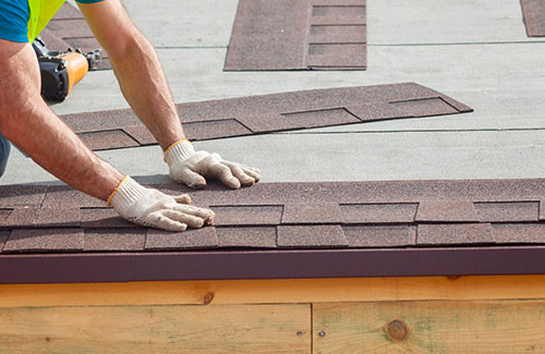 A photo of a roofer installing asphalt shingles on a roof in Calgary.