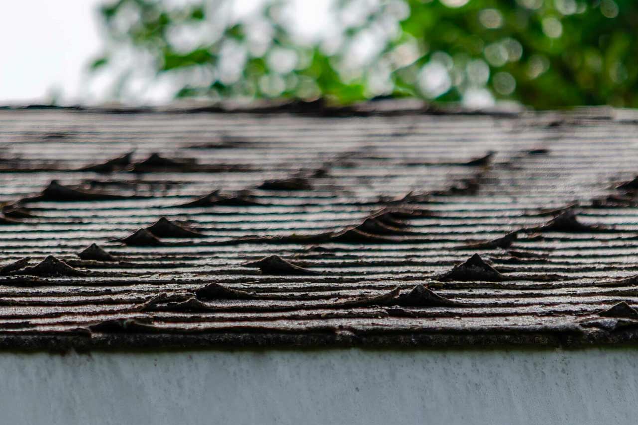 Curled shingles on roof showing signs of old age